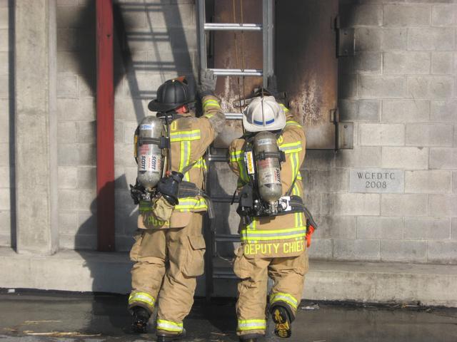 Firefighter John Poole and Deputy Chief Chris Obenchain raising a ladder.